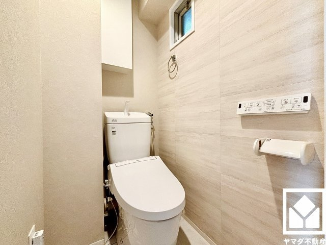 メガロコープ西宮2　1号棟のトイレ|明るく清潔感溢れるトイレです。温水洗浄便座付きで、季節を問わずいつでも温かい便座をお使いいただけます。トイレットペーパーのストックや消耗品置き場などとしてお使いいただける吊戸棚がございます。