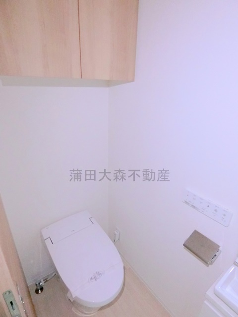 クオリタス南大井のトイレ|吊戸棚収納と温水洗浄便座付きのタンクレストイレ