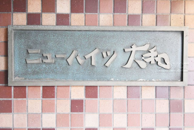 【現況写真】 | ニューハイツ大和 | マンションの入り口に掲げられた、建物名称の表示部分。不動産業界ではこれを「館銘板」と呼びます。～即日のご見学可能～　お問合せはお気軽にどうぞ。
