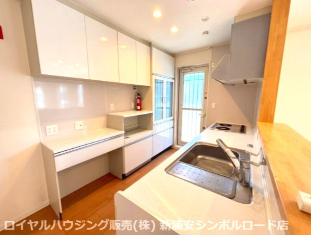 大容量の背面収納と広いカウンターを備えた、ナチュラルホワイトのシステムキッチン。