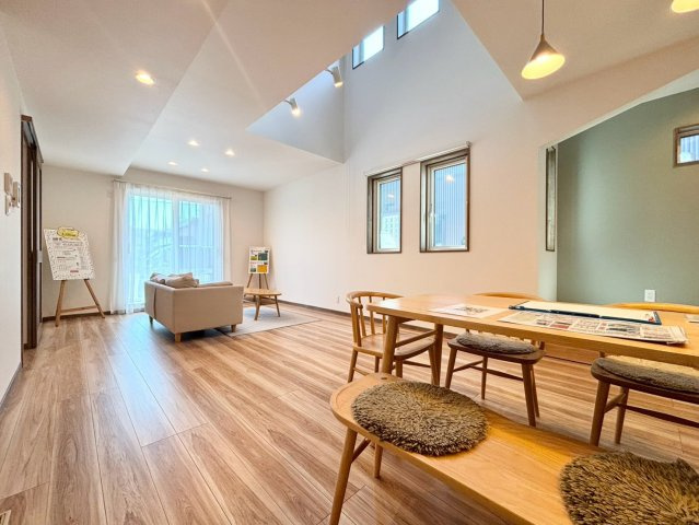 福住２条９丁目　新築戸建の居間・リビング|陽当たりの良い20帖LDK。木目のフローリングや梁、建具、ダウンライトが温もりを演出し、大きな家具を置いてもゆとりのある空間。