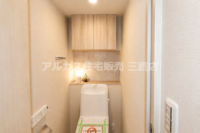 セザール高井戸ガーデンのトイレ|手洗いカウンターと上部吊戸棚を備えた、機能的でスタイリッシュなトイレ。