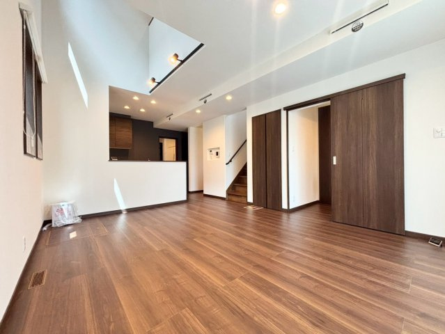 福住２条９丁目　1号棟　新築戸建の居間・リビング|陽当たりの良い16帖LDK。木目のフローリングや建具、ダウンライトが温もりを演出し、大きな家具を置いてもゆとりのある空間。