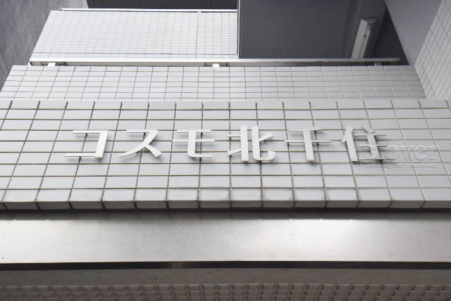 【現況写真】 | コスモ北千住 | マンションの入り口に掲げられた、建物名称の表示部分。不動産業界ではこれを「館銘板」と呼びます。～即日のご見学可能～　お問合せはお気軽にどうぞ。
