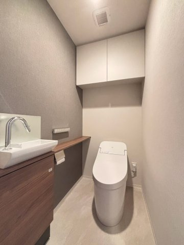 超節水洗浄のウォシュレット一体型タンクレストイレ。手洗いうカウンター付き。片面壁紙がアクセントクロス施工です。