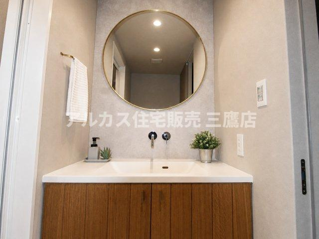 藤和シティホームズ南阿佐ヶ谷の独立洗面台|大きな丸型ミラーが目を引く洗面スペース。木目調の収納扉が空間に温かみを添えます。