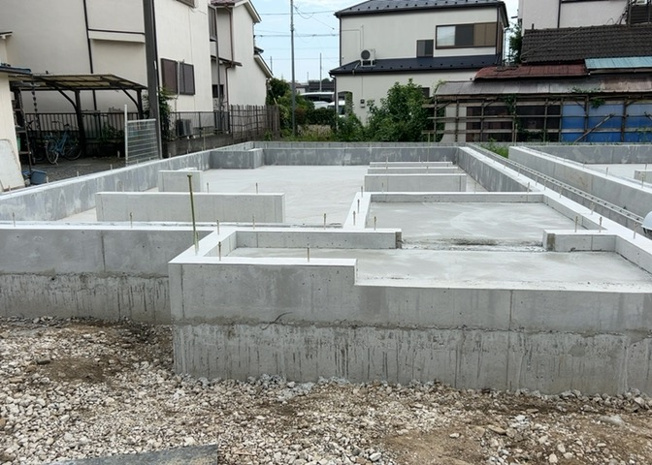 【構造・工法・仕様】 | 暁町新築戸建 | ベタ基礎とは、柱の位置に関係なく全体に基礎がある事を指し、面積が大きい分建物の重さを全体に分散できます。また、地面からの湿気や害虫を遮断でき、木造住宅で心配されるシロアリ被害を防ぐ効果も期待できます。