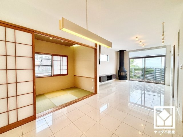 西宮市甲陽園山王町の居間・リビング|存在感のある薪ストーブが印象的なリビング。美しい鏡面タイルの床や、バー型シェードのペンダントライト、ダクトレール照明など、空間デザインへの配慮が感じられるデザイナーズハウスです。