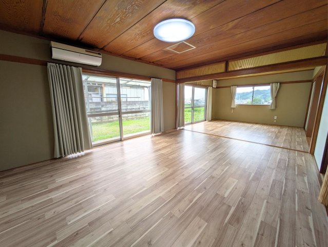 溝辺町戸建ての居間・リビング|木の温もりを感じる天井と大きな窓が解放感を生むリビング。お庭の緑を眺めて穏やかに過ごせます。