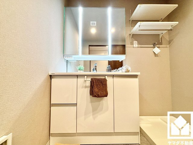 ライオンズマンション西宮高座B棟の洗面所|収納付きでスッキリお使い頂ける3面鏡の洗面台です。縦に2本配置されたLED照明が顔全体を明るく均等に照らしてくれるので、スキンケアやメイクがしやすくなります。