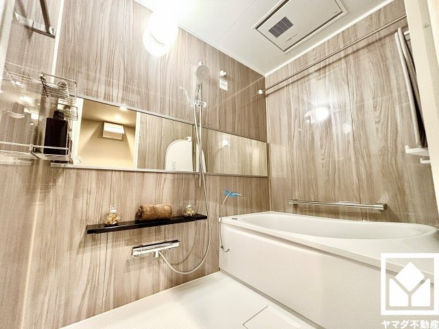 ライオンズマンション西宮高座B棟の浴室|清潔感あふれる空間で、毎日のバスタイムをより快適に。ナチュラルな木目調のパネルは落ち着いた雰囲気を演出してくれます。鏡が横長なので、お子様でも見やすく便利です。