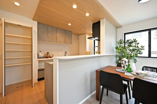 西宮市瓦林町新築一戸建て│南向き4LDK+駐車1台可のキッチン|キッチン上部に折下天井を採用でデザイン性を向上させています。ダウンライトを採用し、作業性を確保。キッチン脇には可動棚収納庫が設けられており、高さを調整して日常品や掃除用品など幅広く収納可能。