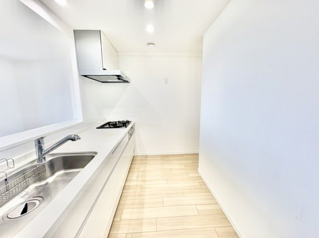 RICイーストコート4番街5番館のキッチン|ご夫婦や親子で並んで快適に料理ができる、ゆとりある通路幅を確保したキッチンスペース。白を基調とした洗練されたデザインで、背面には冷蔵庫やカップボードも配置しやすく、日々の家事動線がスムーズです。