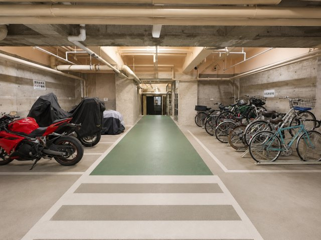 虹ヶ丘マンション本館の駐輪場|建物内に設けられた駐輪場とバイク置場です。屋根付きのため雨風の影響を受けにくく、自転車とバイクのスペースが分けられています。