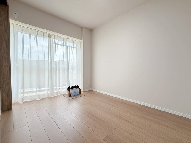 壬生川団地の洋室|木目の自然な模様や落ち着きある色味が、お部屋に温かみをもたらします。壁紙は白を基調としており、インテリアプランも考えやすいシンプルな仕上がりです。（R8.7撮影）