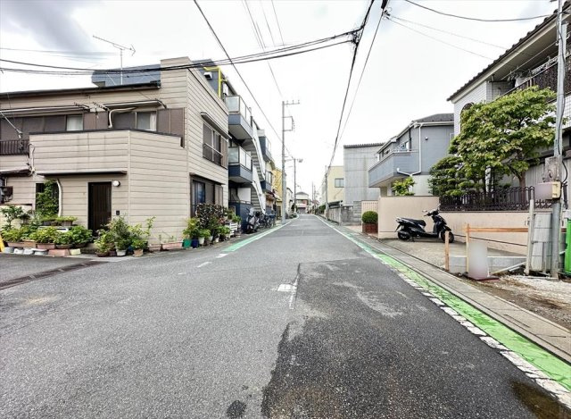 【前面道路含む現地写真】 | 富士見市水谷東3丁目　新築一戸建住宅　全1棟　(志木本店) | 前面道路は幅員のあるゆったりとした道路で、見通しも良好。道路沿いには緑色のラインが施され、歩行者の通行にも配慮された住環境です。周辺は戸建て住宅が建ち並ぶ落ち着いた街並みで、穏やかな暮らしを楽しめます