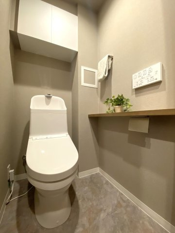 アイディスクエア川越新富町のトイレ|トイレ新規交換
玄関近くの廊下に配置された独立トイレ。新規交換済みの快適な仕様で、上部にはペーパーなどのストックに便利な収納棚も備わっています。