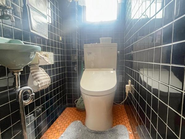 牧2丁目　戸建てのトイレ|落ち着いた色合いのタイルが特徴の手洗い器付きトイレです。窓付きで明るさが感じられます。