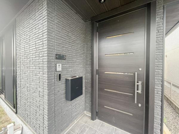 京が丘南4丁目　中古の玄関|シンプルながらも洗練されたデザインの玄関ドアが印象的です。落ち着いた色合いの外壁が特徴でモダンな雰囲気を演出しています。ドア横にはポストやインターホンも設置されており機能性にも配慮されています。