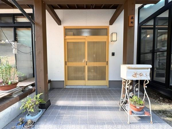 政所　中古の玄関|広々とした玄関スペースが印象的です。格子戸が風通しを感じさせ明るい雰囲気が特徴です。屋根付きで雨の日も安心の設計です。
