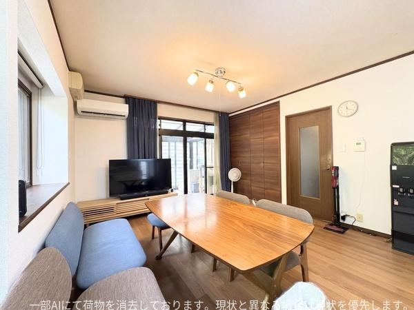政所　中古の居間・リビング|大きな窓から自然光が差し込むリビングです。落ち着いた内装と木目のテーブルが調和しています。テレビスペースもありゆったりとした空間が広がっています。