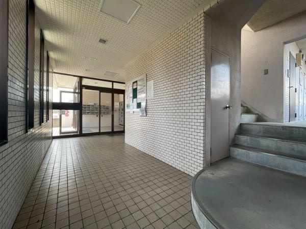 グレイス弐番館のエントランス|広々としたロビーは白色のタイル壁が印象的です。明るい雰囲気で掲示板も設置されています。大きなガラス扉からたくさんの光が差し込みます。階段もすぐ近くにあり動線も分かりやすいです。清潔感のある空間です。