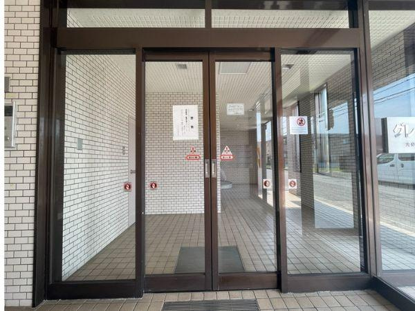 グレイス弐番館のエントランス|エントランスはガラス扉で開放感のある雰囲気です。明るいタイル貼りの内装が清潔感を感じさせます。道路からのアクセスもスムーズです。共用部分がよく手入れされている印象です。