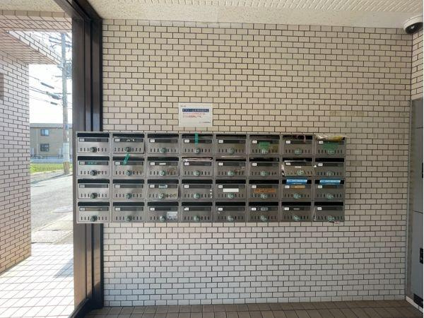 グレイス弐番館のエントランス|エントランスには複数の郵便ポストが並び使いやすい配置となっています。清潔感のある白いタイルが印象的です。日当たりも良く明るい雰囲気が感じられます。オープンスペースが広がりゆったりとした空間です。