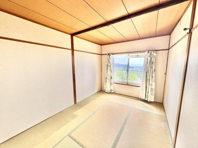 渦ヶ森コーポ壱号棟の和室|窓の外に美しい景色が広がる、眺望良好な約6帖の和室。遮るものがないため開放感にあふれ、心地よい光と風が部屋中に通り抜けます。畳の上でゆったりと寛ぎながら、贅沢なパノラマを楽しめます。