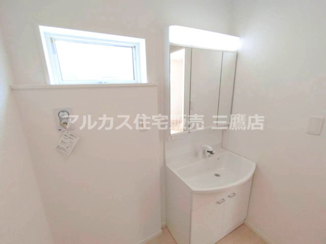 調布市富士見町3丁目 京王線 西調布駅 新築戸建の独立洗面台|三面鏡付き洗面化粧台と便利な小窓を備え、毎朝の身支度が快適に行える清潔な洗面スペースです。