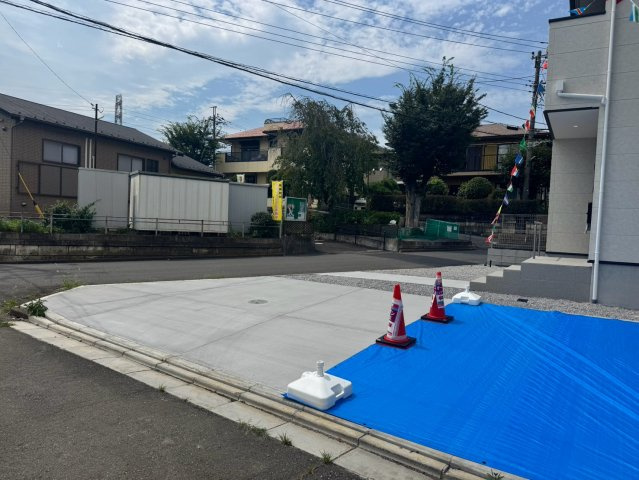 入間市宮寺新築戸建の前面道路含む現地写真|解放感あふれる角地に位置し、お車の出し入れもスムーズな幅員約6m＆約4.9mのゆとりある前面道路！日当たりや通風も良好で、毎日の生活や駐車を快適にサポートしてくれる大変魅力的なロケーションです。