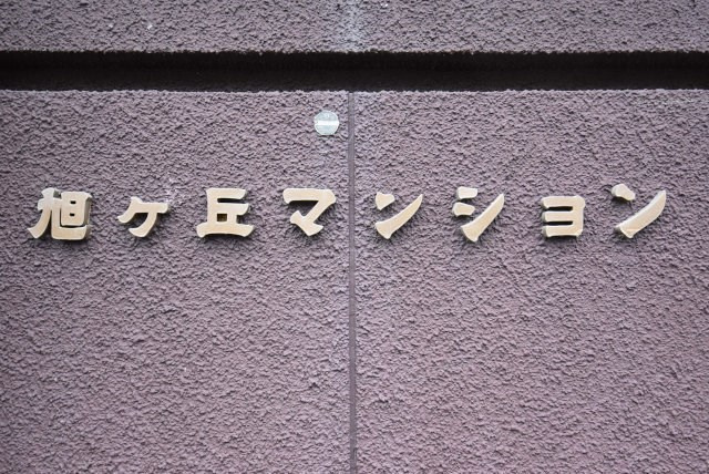 【防犯設備】 | 旭ヶ丘マンション | マンションの入り口に掲げられた、建物名称の表示部分。不動産業界ではこれを「館銘板」と呼びます。～即日のご見学可能～　お問合せはお気軽にどうぞ。
