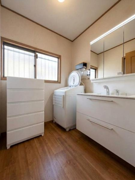 横浜市青葉区大場町の中古一戸建の独立洗面台|収納力のある洗面台とキャビネットで整理整頓しやすい洗面所です。明るい照明と大きな鏡が空間に広がりを与えます。洗濯機の配置も効率的です。窓からの採光も期待できます。