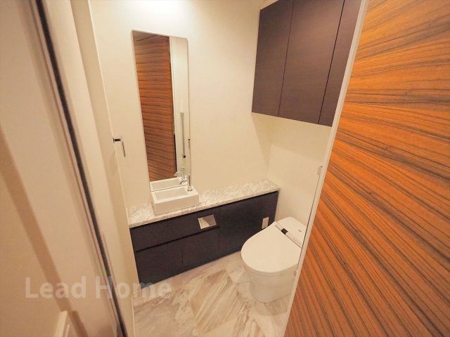 【トイレ】 | シティタワー麻布十番 | 手洗いカウンターと上部棚を備えたスタイリッシュなトイレです！清潔感のある空間で快適に使えますね♪