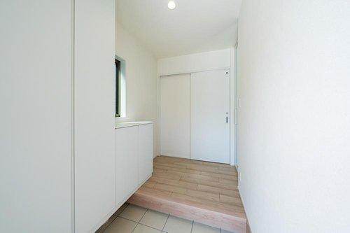 【秀光ビルド】港区東茶屋分譲鉄筋コンクリート住宅C棟の玄関|玄関ホール・下駄箱：◎毎日の出入りが楽しくなる、ホワイトカラーでまとめられたおしゃれな玄関♪靴も荷物もすっきり片付き、家族みんなが笑顔に。（2026年2月）撮影