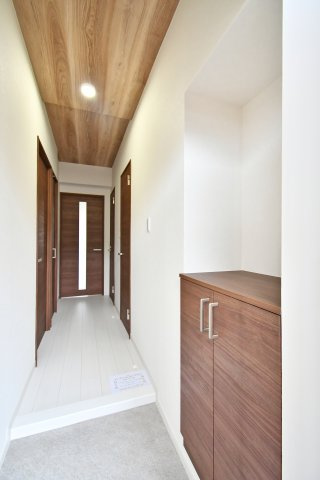 蓮田ビューパレーA棟の玄関|木目調の天井と建具が温かみを演出する、玄関からつながる明るく落ち着いた廊下です。シューズボックスも完備されており、家族みんなが使いやすい機能的な玄関となっています。