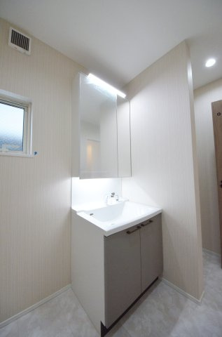 丹那町の独立洗面台|清潔感あふれるシャワー付洗面台と洗面室。鏡の裏には、歯ブラシや化粧品、ドライヤーまでスッキリ収まる大容量の収納スペースがあります。