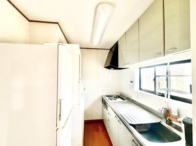 中古戸建　伊丹市池尻3丁目のキッチン|上下に豊富な収納を備えたシステムキッチン。調理スペース前に窓があり明るく気持ちよくお料理を楽しめます。