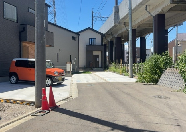 【前面道路含む現地写真】 | 前面道路は幅6ｍ以上の公道となっており、開放感のある角地風のロケーションです。車同士のすれ違いや庫入れもスムーズで、小さなお子様がいるご家庭でも安心の前面道路環境。周辺は平坦地で徒歩移動も楽々です。