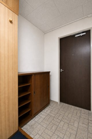 木目調の収納を備えた、すっきりとした清潔感のある玄関空間。※現地の撮影写真を基にCG加工編集済