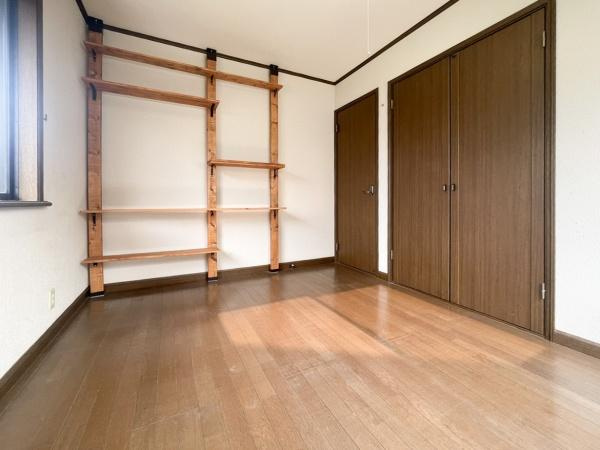 高江中央2丁目中古の洋室|洋室には棚が設置されており整理整頓に便利です。床や扉も落ち着いた色合いで統一感があります。窓から自然光が差し込む明るい空間です。クローゼット付きで収納力も期待できます。