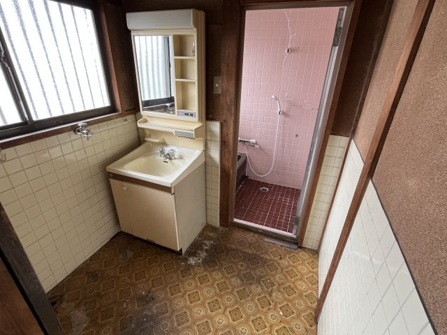 愛知県東海市加木屋町郷中　～新駅「加木屋中ノ池」駅が身近。自然と利便性が共生する街～の脱衣所|レトロな幾何学模様のクッションフロアが懐かしさを感じさせる脱衣スペース。時代を感じる洗面台や木製の柱