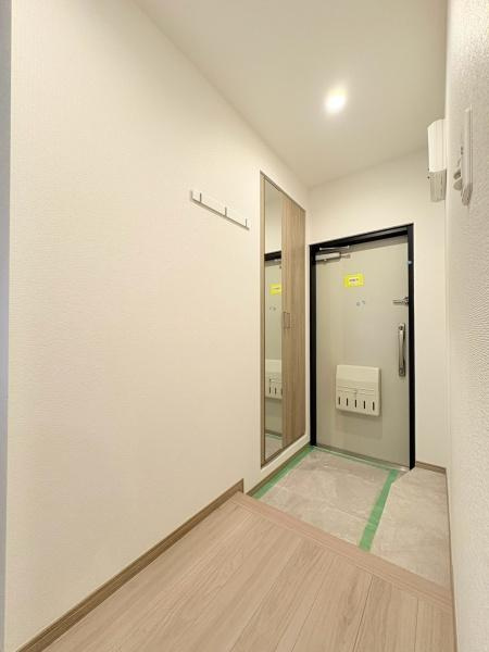六会駅前高層住宅の玄関|玄関には全身鏡付きの収納スペースがあり身だしなみのチェックに便利です。白を基調とした内装が空間に明るさを与えています。シンプルなデザインで清潔感のある印象です。