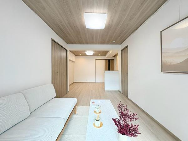 六会駅前高層住宅の居間・リビング|ナチュラルな木目天井が印象的なリビングです。白を基調とした壁と床が室内をすっきりと引き立てています。ゆとりある空間構成が感じられます。使い勝手の良いレイアウトでコーディネートしやすい雰囲気です。