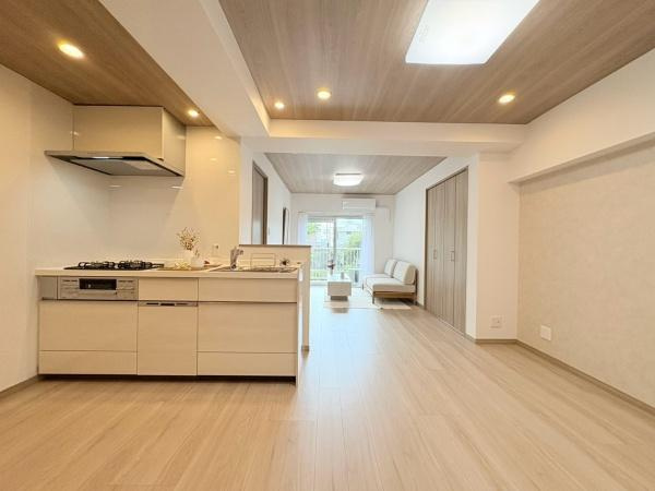 六会駅前高層住宅の居間・リビング|ナチュラルな木目調のフローリングが優しい印象を与えるリビングです。開放的な間取りでキッチンからリビング全体を見渡せます。大きな窓から光が入るため日中は明るさを感じられます。