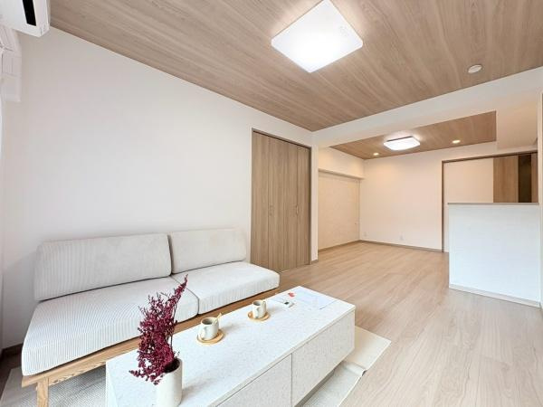 六会駅前高層住宅の居間・リビング|約14.5帖のリビングダイニングキッチンです。やわらかな木目調の天井が印象的な空間です。シンプルなデザインが魅力的です。家具の配置もしやすい間取りです。ソファセット、エアコン1台付き。