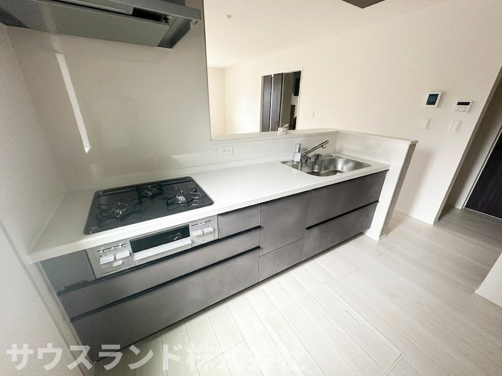 八王子市四谷町2期　のキッチン|シックなダークカラーのデザインが美しい、収納力抜群のシステムキッチンです！大きなお鍋やフライパン、調理器具などもすっきりと片付けることができます。作業スペースも広く、効率よくお料理が進められます。