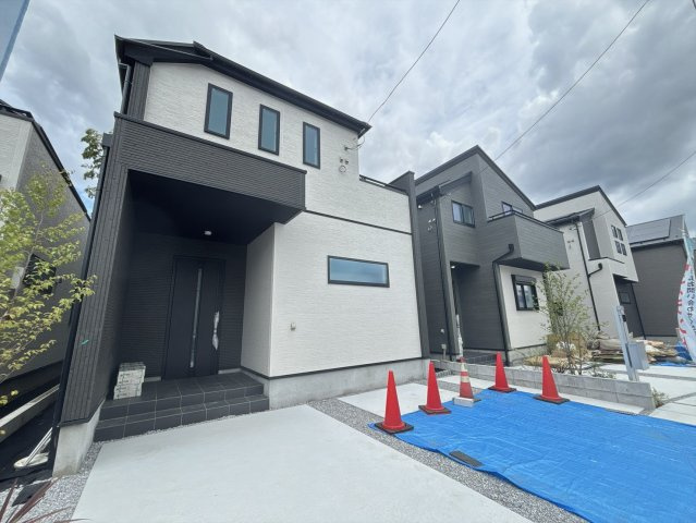 八王子市四谷町2期の外観|左側から見た外観写真です。建物の立体感や窓の配置を確認いただけます。手前には広い駐車スペースがあり、車を2台停めてもまだ余裕のある広さです。青空の下で明るい印象の住まいです！