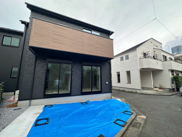 八王子市万町第１期のその他|足場が外れ、建物の美しい外観が見えてきました！シックでモダンな色合いが青空によく映えます。玄関周りのアプローチもゆとりがあり、自転車を置いたりベビーカーを畳んだりするスペースとして重宝します♪