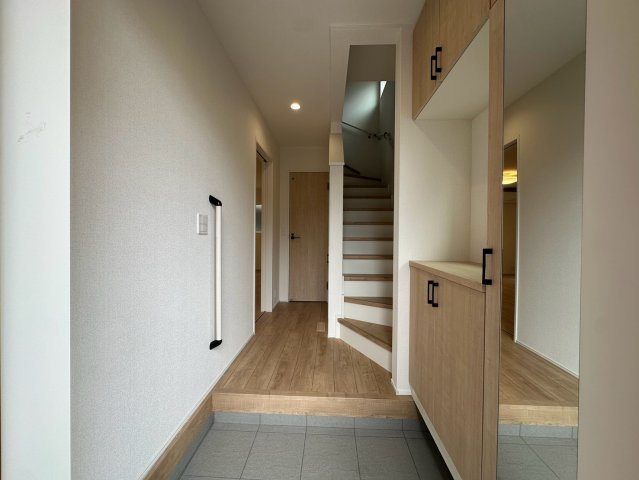 八王子市万町第１期の玄関|木の温もりが感じられる明るい玄関ホールです！天井まである大容量のシューズボックスを備えており、ご家族全員の靴もすっきりと収納可能。ベビーカーや外遊びのおもちゃも置けるゆとりのある広さが嬉しいです♪